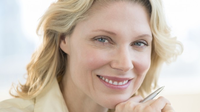 Businesswoman With Hand On Chin Smiling In Office