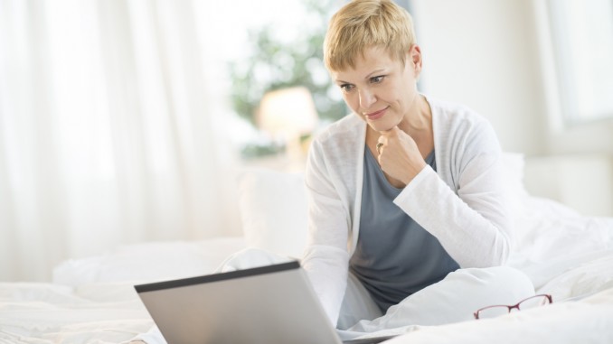 Woman Surfing On Laptop In Bedroom