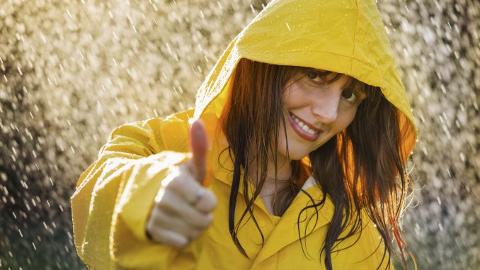 woman wearing yellow raincoat out in the rain Smile, positive attitude, optimism